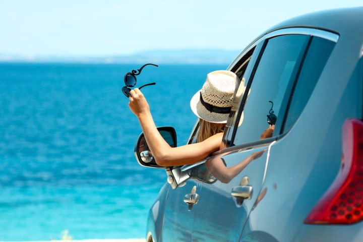 Frau im Mietwagen am Strand